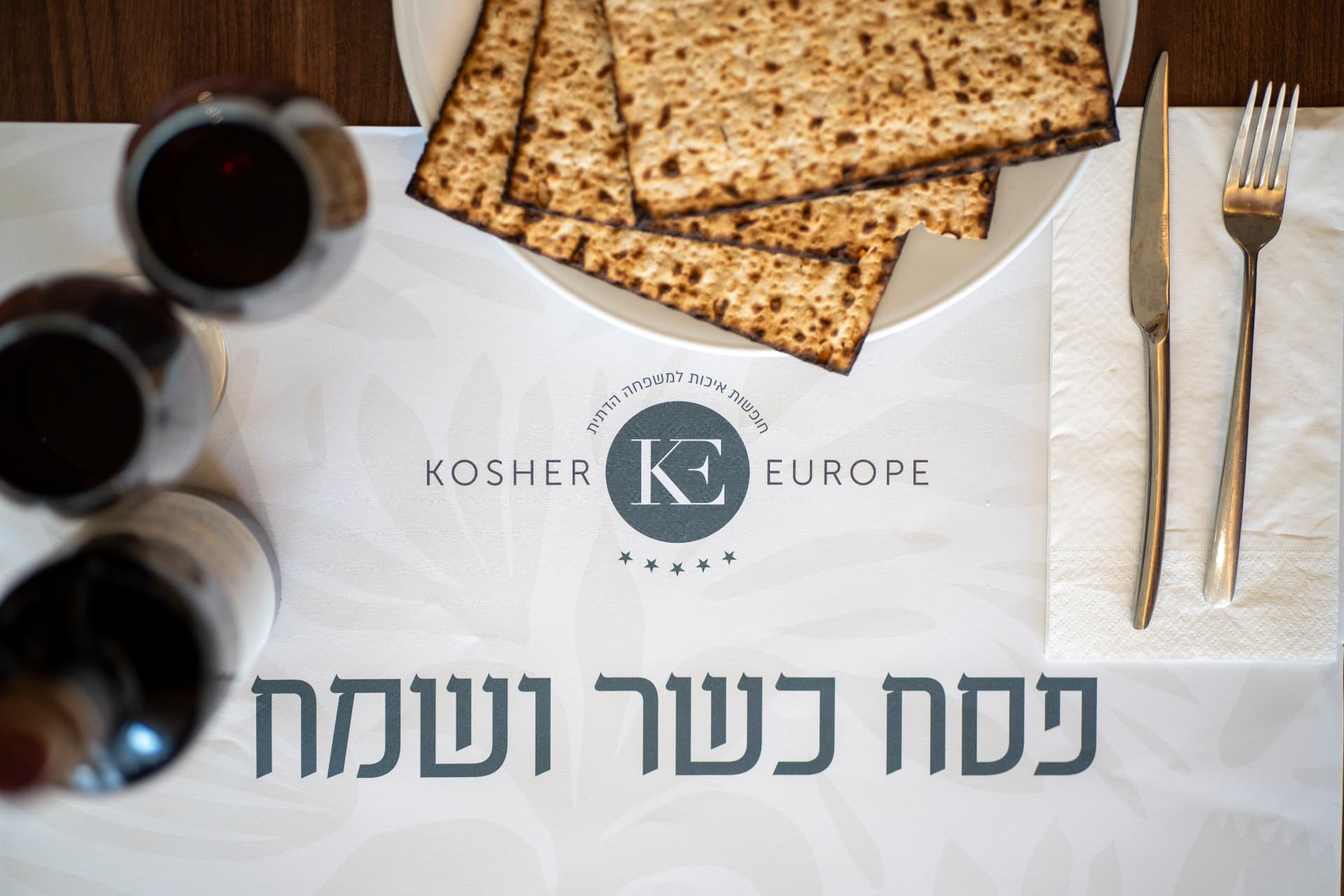 מפת שולחן של כושר יורופ עם הכיתוב פסח כשר ושמח, מצה וכוס יין
